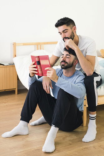 guapo-joven-pareja-gay-juntos-leyendo-libro-dormitorio_23-2148083197