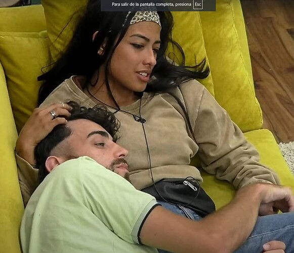 La imagen muestra un paisaje natural sereno con un lago tranquilo y un bosque denso de árboles, rodeado de <tag> montañas </tag> y <tag> nubes </tag> blancas en el cielo. (Subtitulado por IA)